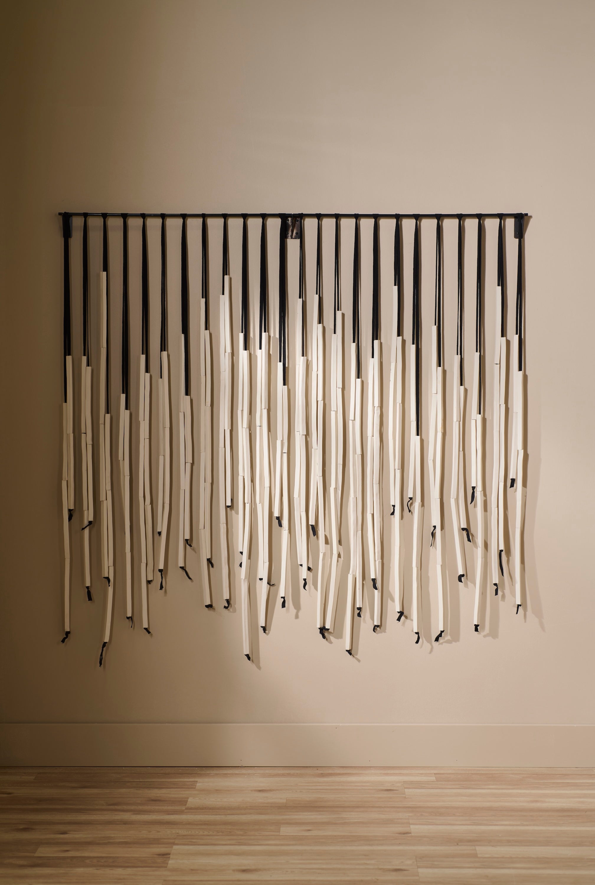 Counterpoint 3 by Lauren HB Studio — handmade porcelain wall sculpture with raw unglazed porcelain rods suspended from a custom blackened metal bar, displayed in a neutral interior.