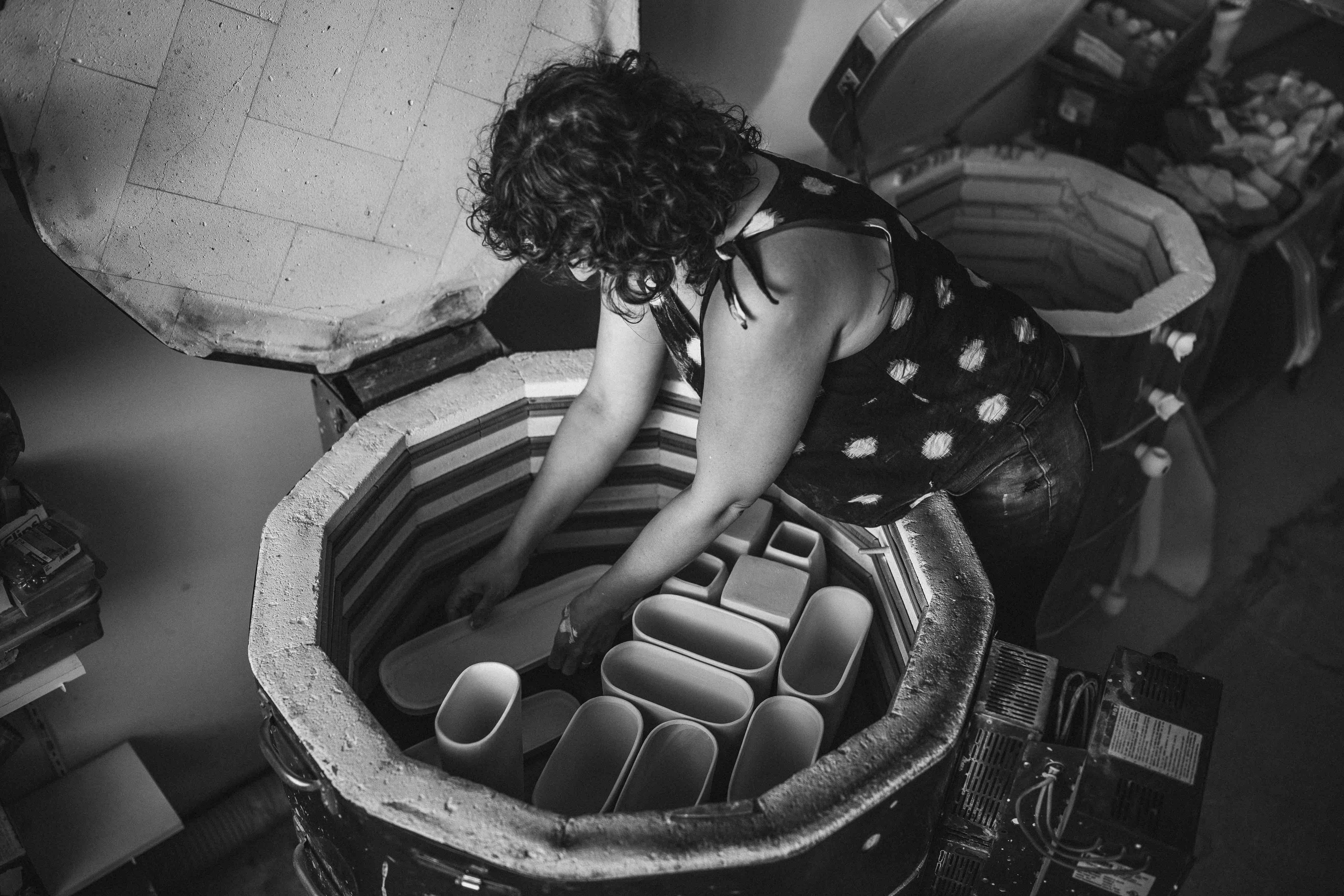 Ceramic artist loading porcelain vessels into a kiln at Lauren HB Studio in Lakewood, Ohio, part of the handcrafted sculpture process.