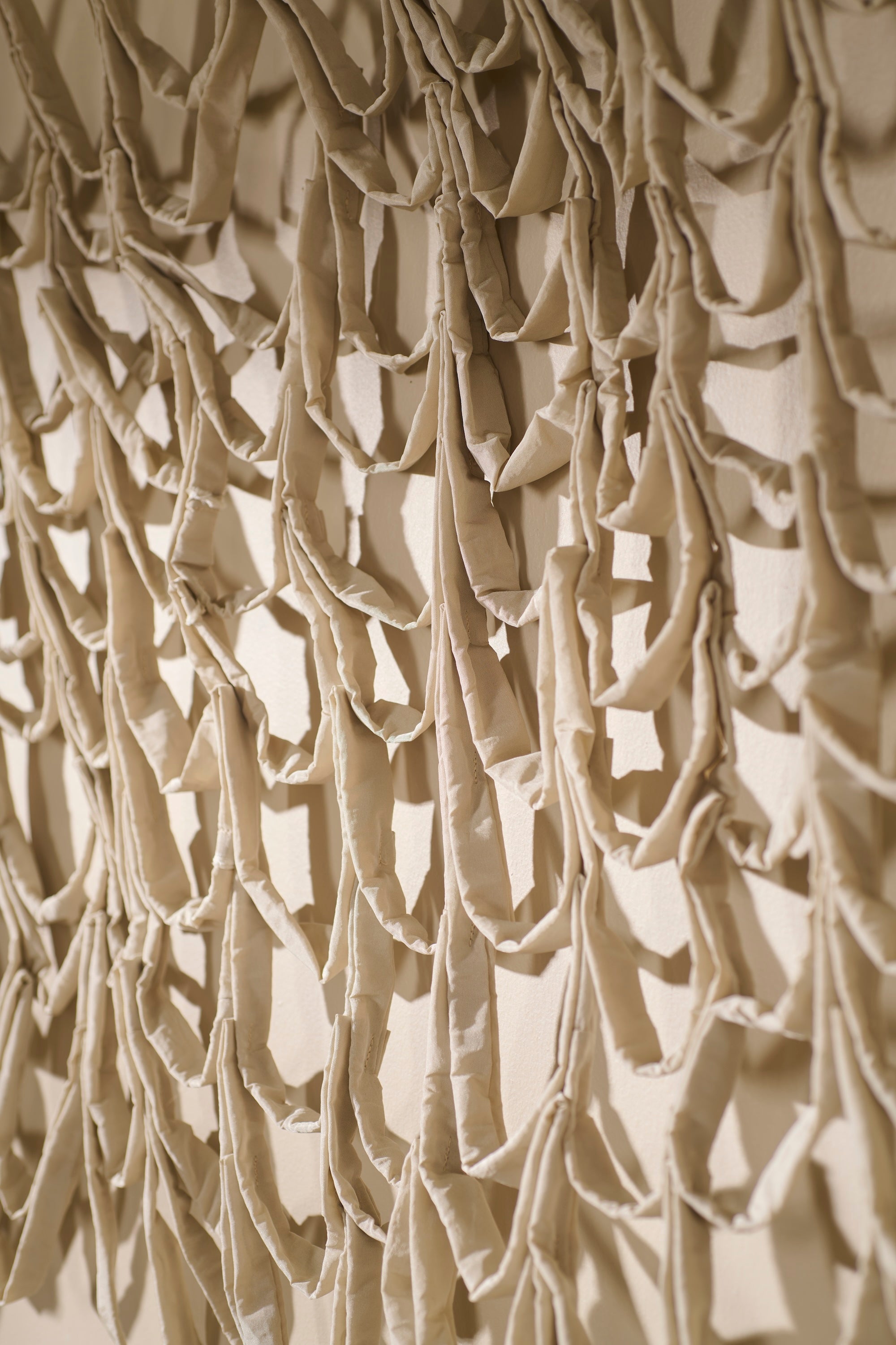 Angled close-up view of Murmur 2 by Lauren HB Studio — handmade fabric wall sculpture featuring rhythmic folds and layered repetition. Soft studio lighting accentuates the shadows and organic movement of the sewn forms.